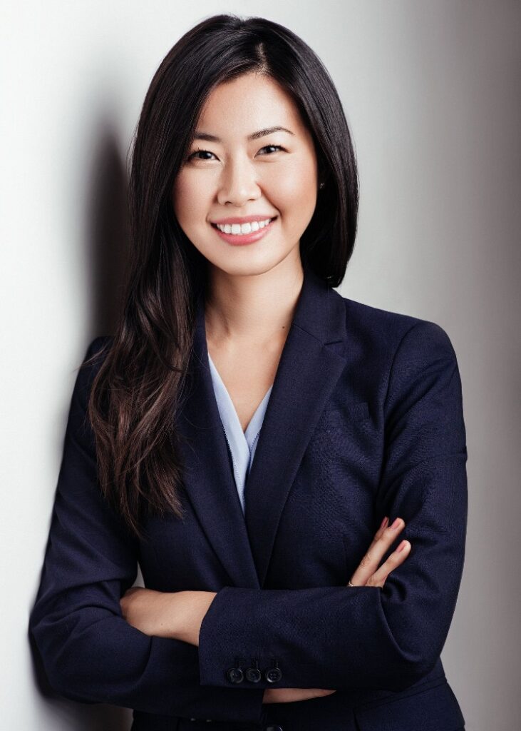 Asian female in black suit with grey background.